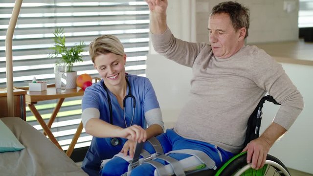 Healthcare worker and paralysed senior patient in hospital, applying orthosis.