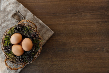 Easter natural eggs in basket on brown wooden background and sackcloth