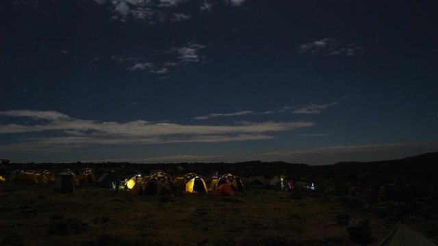 Pitched tents camping at the base of Mount Kilimanjaro. Beautiful timelapse view of the clouds moving over the tents.