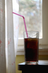 Glass of soda with straw at home. Selective focus.