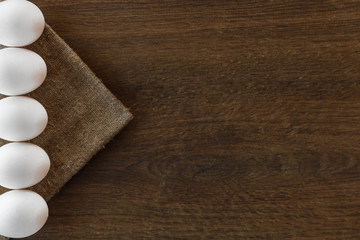 Easter white eggs line on brown wooden background and sackcloth. 