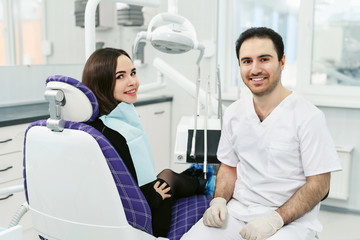 Portrait of a friendly smiling male dentist with patient in the office of a modern dental clinic.