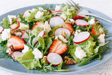 Light spring salad on a white background. Proper nutrition. Diet. Proper nutrition. Diet. Slat with greens, strawberries, radish and cheese
