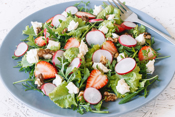 Light spring salad on a white background. Proper nutrition. Diet. Proper nutrition. Diet. Slat with greens, strawberries, radish and cheese