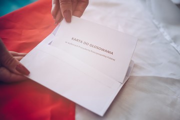 Woman putting correspondence postal ballot paper to envelope.