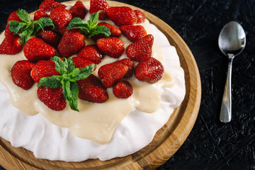 Dessert Anna Pavlova with strawberries on a black background