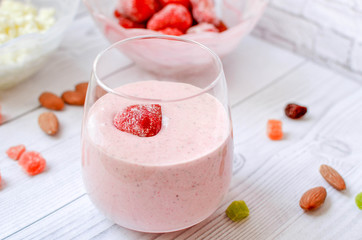 Strawberry smoothie with berry in a glass on a white wooden table. Healthy eating.