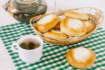 Bun with cottage cheese and tea with mint and berries. Cheesecakes. Homemade baking