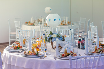 Beautiful white round table at the restaurant. Wedding reception day. Champagne and floral composition