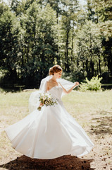 the bride in a white dress stands with her back to us and holds a bouquet of flowers