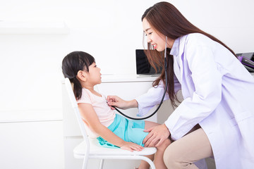 Fototapeta premium The female doctor is examining the girls. Female doctor examining little girl with stethoscope. young woman doctor examining a child patient in white room.