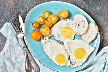 fried eggs and yellow cherry tomatoes. on a blue plate. yellow and blue. top view