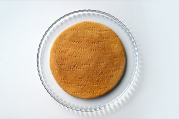 Round baked cake layer on a plate. Homemade cooking honey cake.