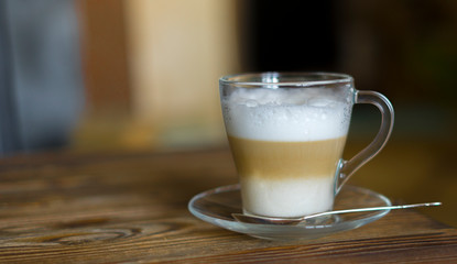 Latte on Rustic Wooden Table. Glass cup on glass saucer with a spoon coffee latte. Shallow depth of field.