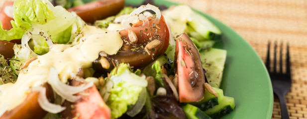 vegetable salad of greens, tomatoes and cucumbers on a green plate