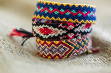 Group of handmade homemade colorful natural woven bracelets of friendship isolated on jute background