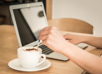 Home office, woman drinks a cup of coffee while working from home