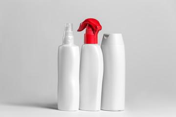 Set of cosmetic products in white and grey containers on light background.