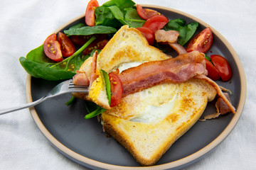 Egg in a hole bread and bacon with salad