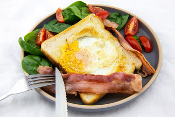 Egg in a hole bread and bacon with salad