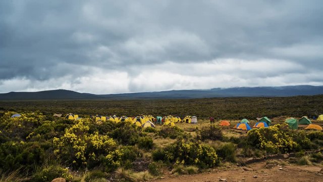 Pitched tents camping at the base of Mount Kilimanjaro. Beautiful timelapse view of the clouds moving over the tents.