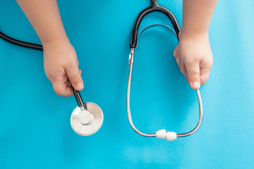 Children's hands hold a medical stethoscope on a blue background