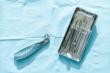 Dental instruments in stainless steel tray on blue background close up copy space