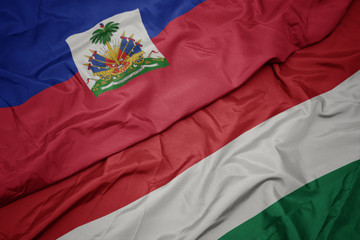 waving colorful flag of hungary and national flag of haiti.