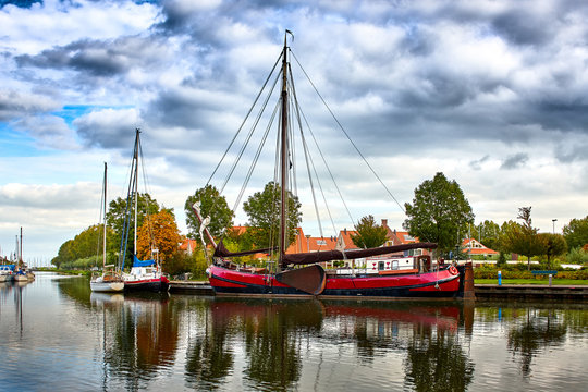 Image of Boats/Dutch Sailing Tjalk on the canal in Amsterdam with buildings and trees. Netherlands, Holland