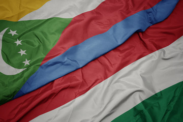 waving colorful flag of hungary and national flag of comoros.