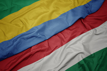 waving colorful flag of hungary and national flag of gabon.