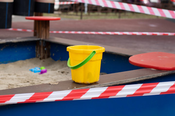 Stop coronavirus, quarantine and prohibition of walking, prevention of infection of the coronavirus covid-19 virus. Quarantine children sandbox, plastic toy bucket and striped barrier tape.