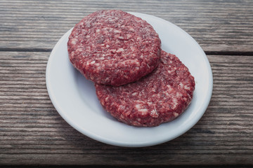 raw burger minced red meat on wooden background on plate