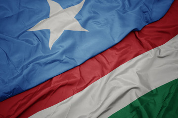 waving colorful flag of hungary and national flag of somalia.