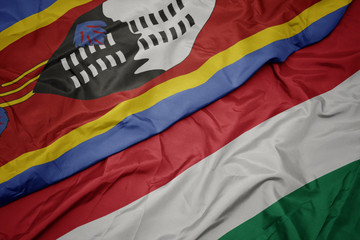 waving colorful flag of hungary and national flag of swaziland.