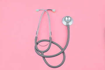 Normal image of one single normal stethoscope isolated on top of a pink color paper background