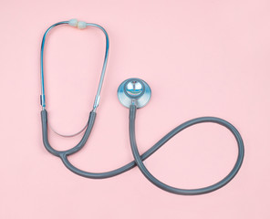 Portrait of one single normal stethoscope isolated on top of a pink color paper background