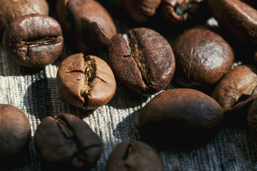 Roasted coffee beans are scattered on the table close-up. Photo in bright sunlight in the morning.