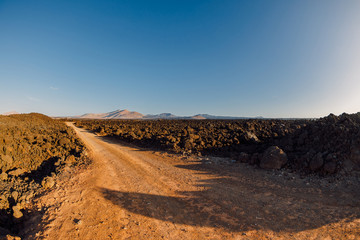 Aerial view of lava fields with dirty road and volcanos. Lanzarote, Canary Islands.