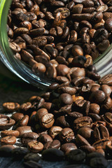 A glass jar of coffee lies on the table and coffee beans are scattered. Photo in bright sunlight in the morning.