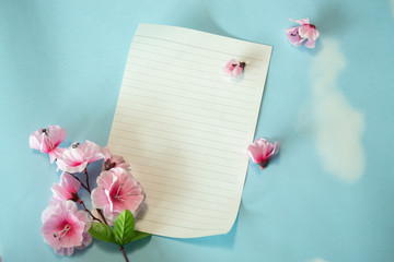 Top view of blank paper and flower bouquet on blue background, copy space