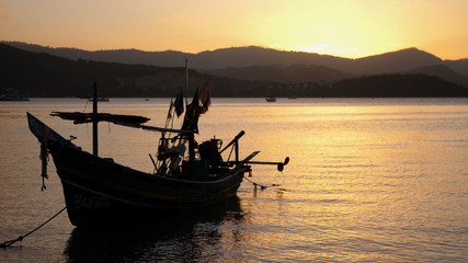 Naklejka premium boat near the shore against the backdrop of mountains and beautiful sunset. Romantic atmosphere. Calm and pacifying scene.