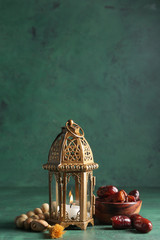 Muslim lamp and tasbih with dates on color background