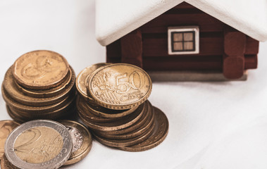 scandinavian house model put behind the pile of euro coins, mortage loan or  real estate investment concept