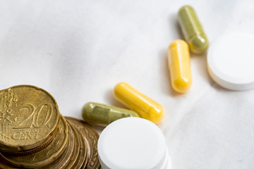 concept of healthcare system recovery for COVID-19 crisis in EU, euro coins stacked and pills on clean and nice white textile fabric.