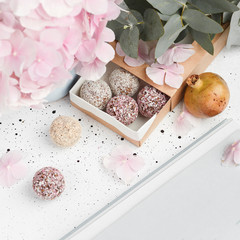 Healthy round candy without sugar, in a box. On a white background. There are flowers nearby.