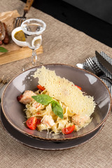 Pasta fettuccine with salmon and tomato on grey plate on the table at restaurant