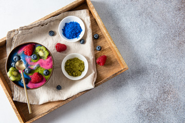 Matcha green tea and blue spirulina breakfast superfoods smoothie bowl topped with kiwi, raspberries and blueberries. Detox, dieting. Top view, flat lay, copy space