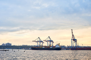 Cargo container terminal of sea freight industrial port. Lifting cargo cranes