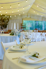 Table set with blank guest card, plate with white napkin and cutlery on table, copy space. Place setting at wedding reception. Table served for wedding banquet in restaurant
